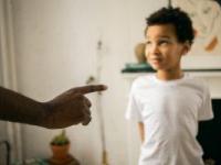 upset little ethic boy looking at faceless father during argument