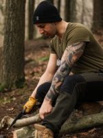 man cutting a branch with a knife in forest