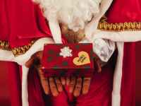person wearing santa claus outfit while holding christmas gift