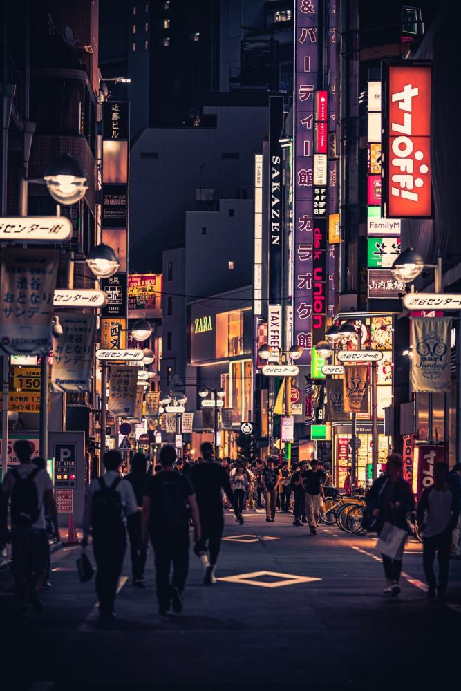people walking on the street between buildings