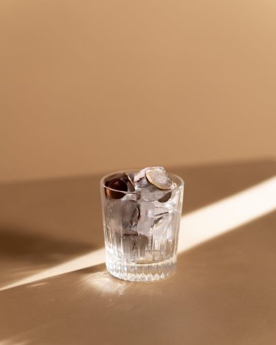 clear shot glass with ice cube and coins