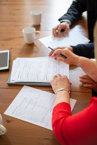 woman in red long sleeve shirt and man in black shirt signing papers