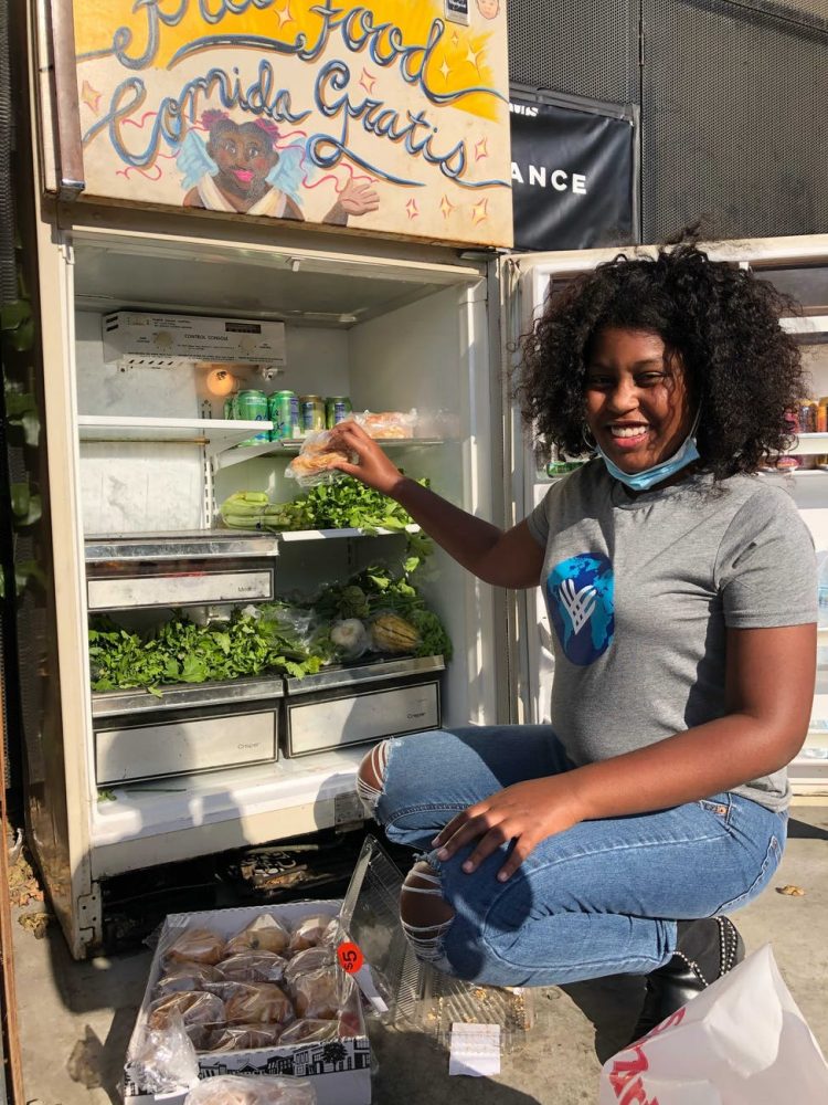 a black female activist looking at camera next to a food bank