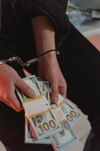 person in handcuffs holding bundles of cash