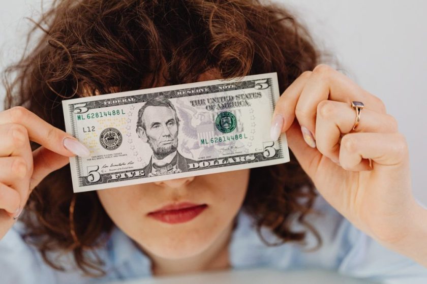 woman covering her face with a dollar bill