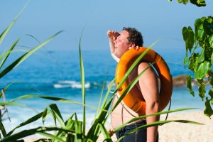 orange safety ring on man shoulder near body of water